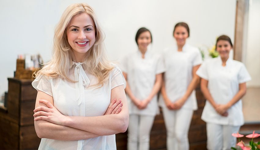 A spa manager smiling in a spa with her staff behind her